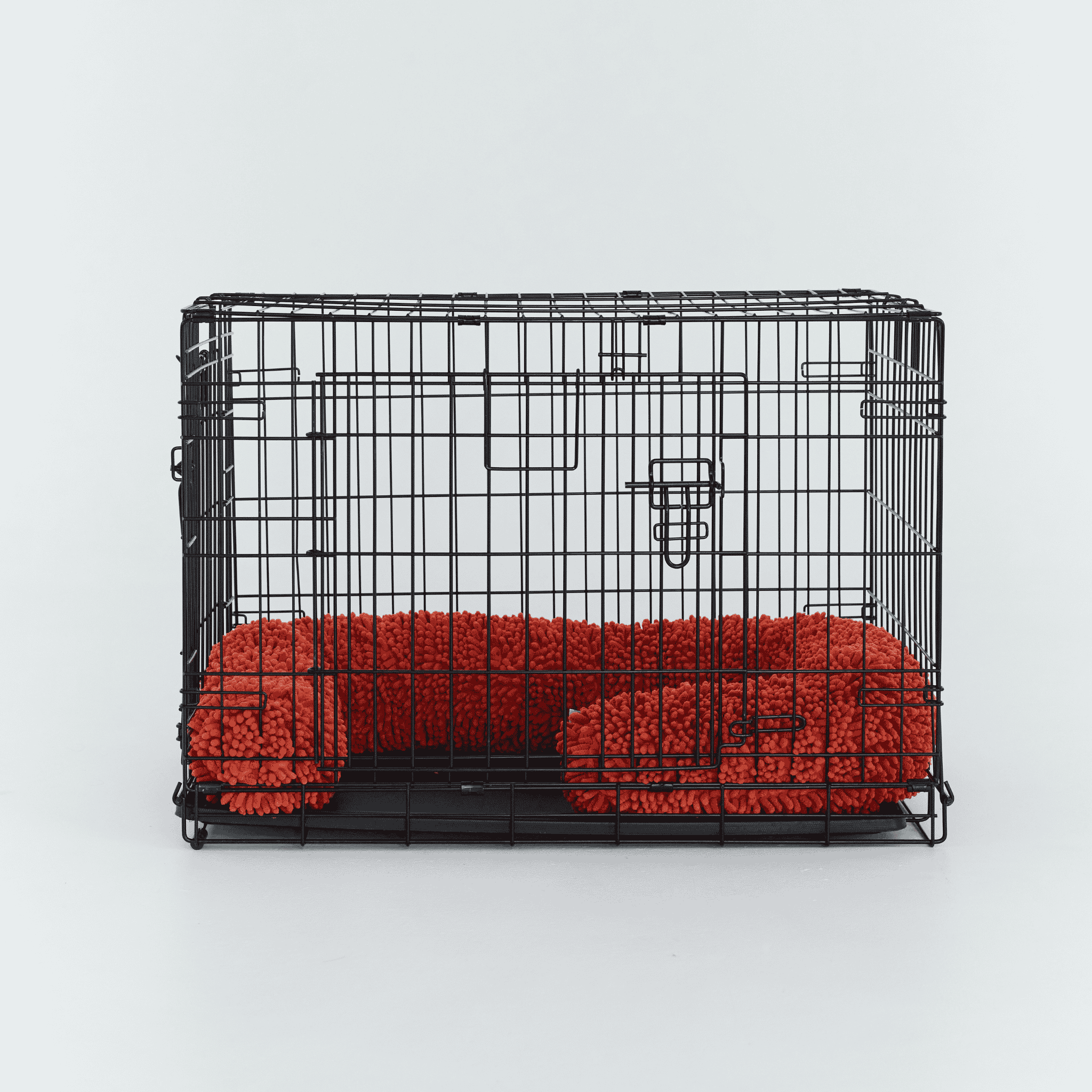 A black wire dog crate fitted with a Burnt Orange CrateSnake Original a memory foam crate cushion.