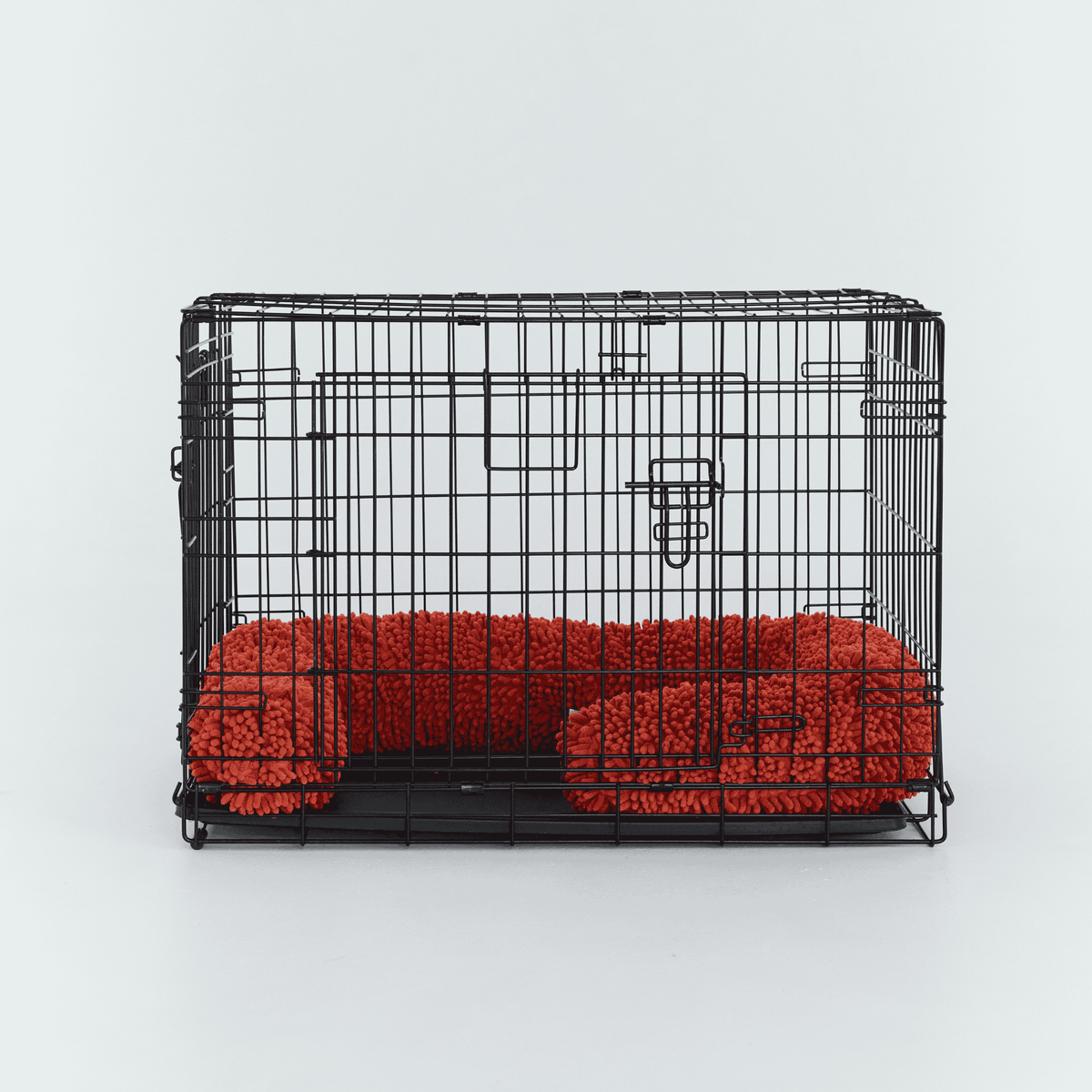 A black wire dog crate fitted with a Burnt Orange CrateSnake Original a memory foam crate cushion.